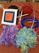 Fiber crafting supplies on a table. Needles, yarn, loom, etc.