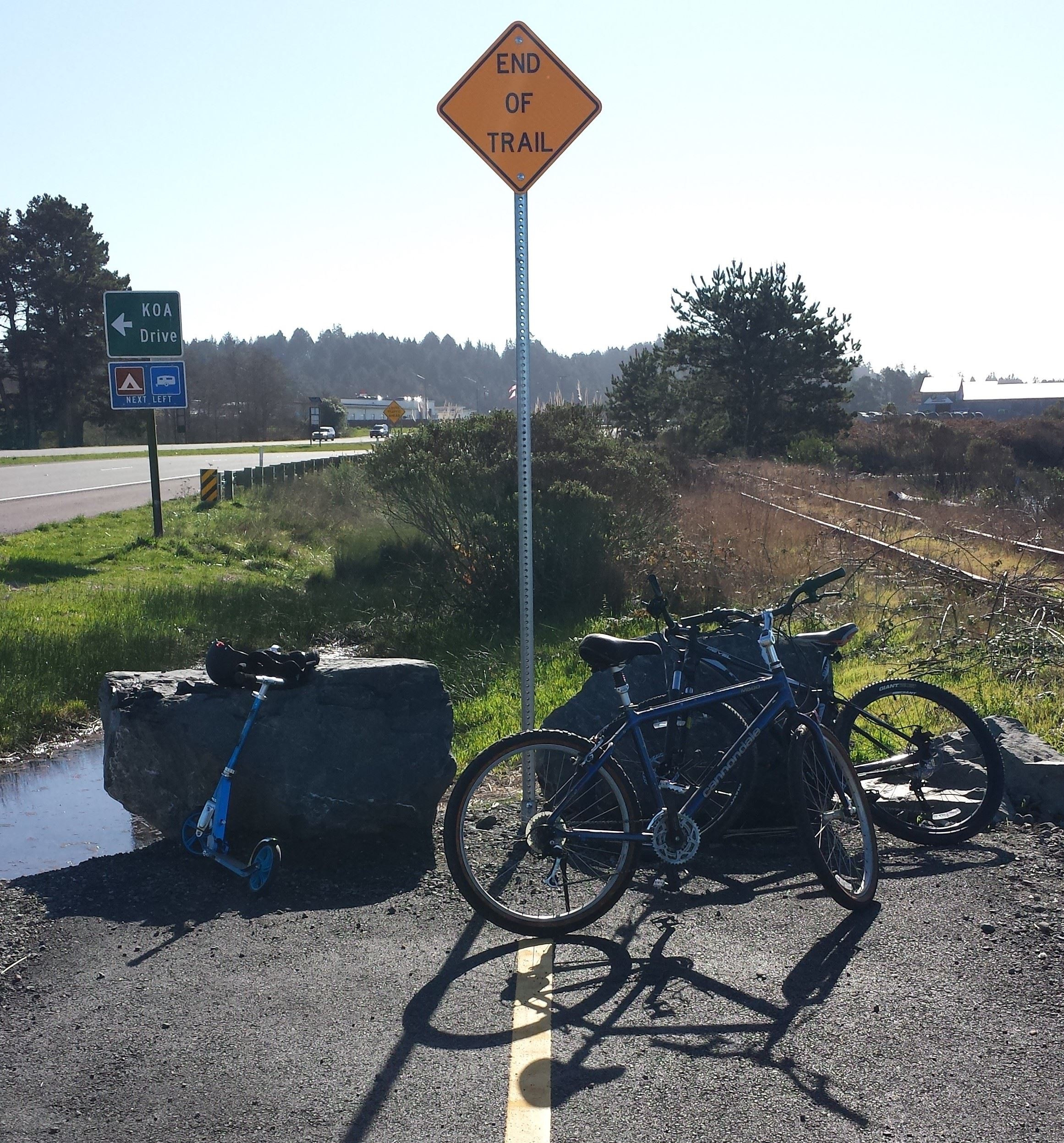 end of trail sign with bikes and scooter