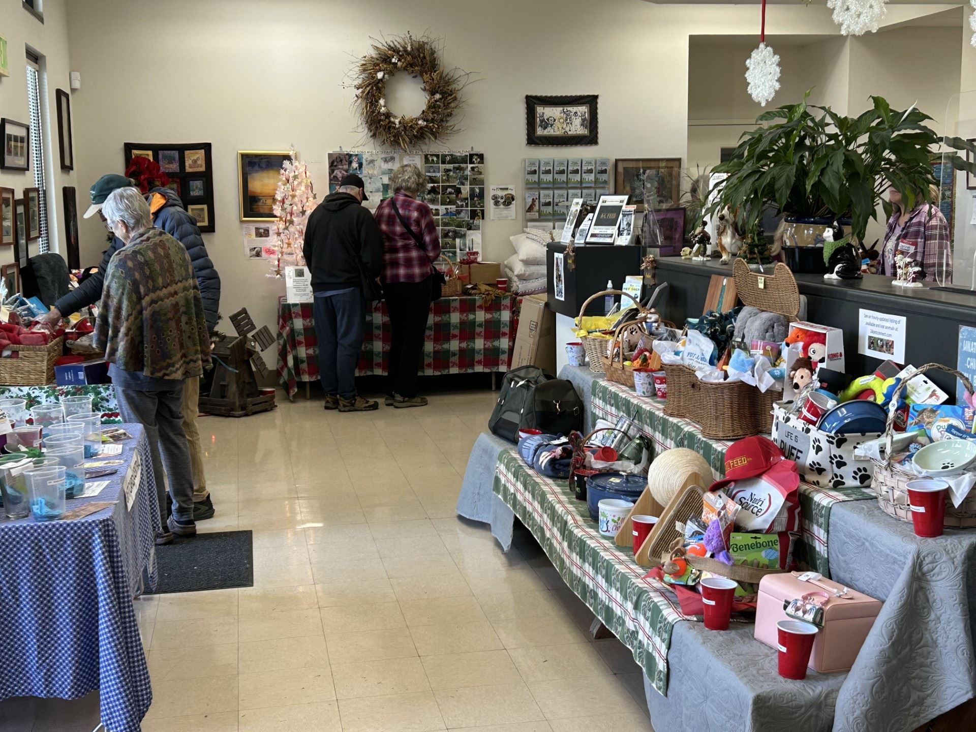 Shelter lobby with Christmas decorations, table displays of assorted raffle prizes and attendees